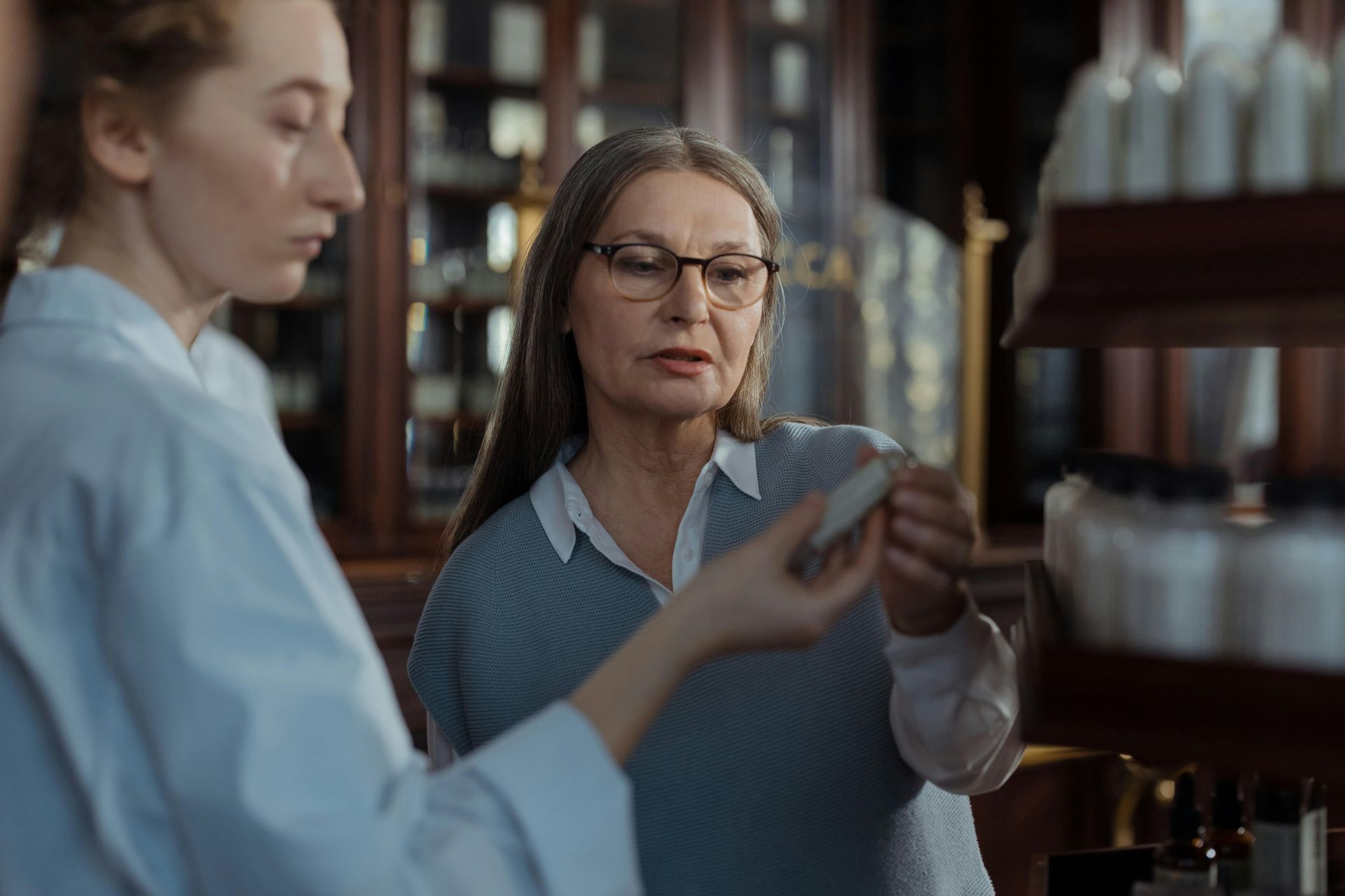 Two women are looking at a bottle of perfume in a store.