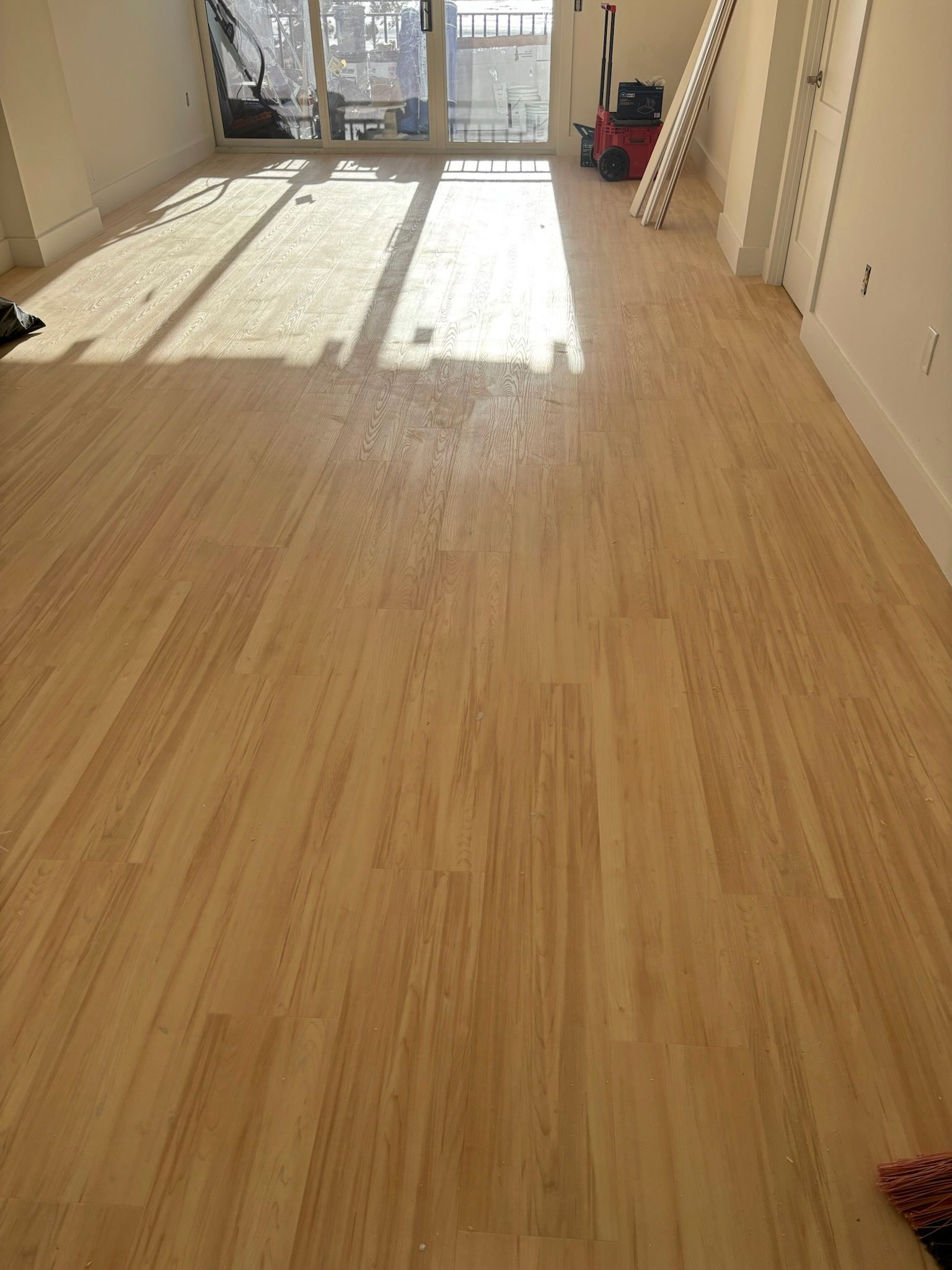 Light wood floor in a sunlit room, viewed from above.