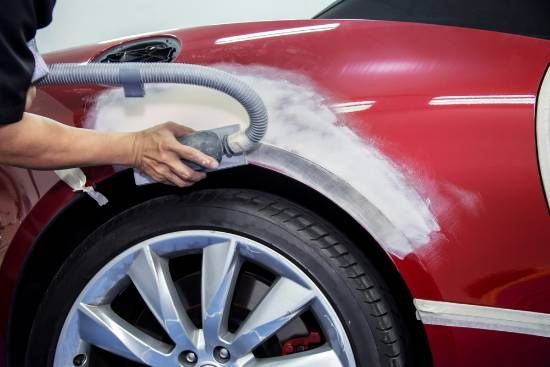 A Person is Sanding the Fender of a Red Car With a Sander— High Grade Tyre and Mechanical in Toowoomba City, QLD