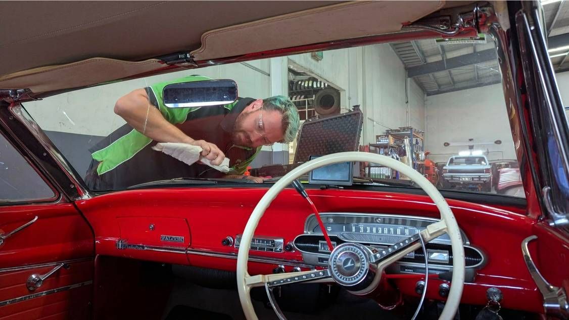 A Man is Working on the Windshield of a Red Car — High Grade Tyre and Mechanical in Toowoomba City, QLD
