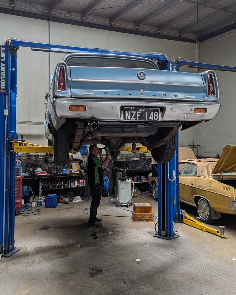 A Man is Working on a Car Lifted in a Garage — High Grade Tyre and Mechanical in Toowoomba City, QLD