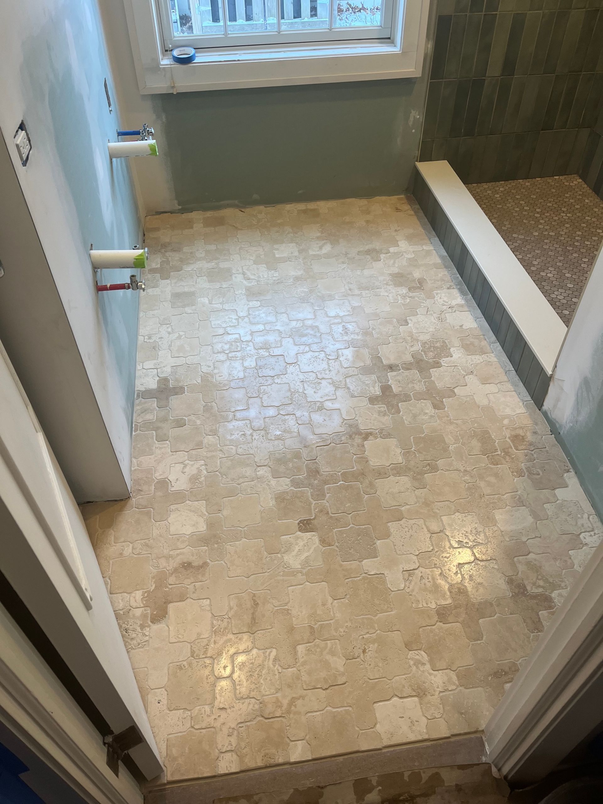 Bathroom floor with light-colored tile; a shower and blue wall are visible.