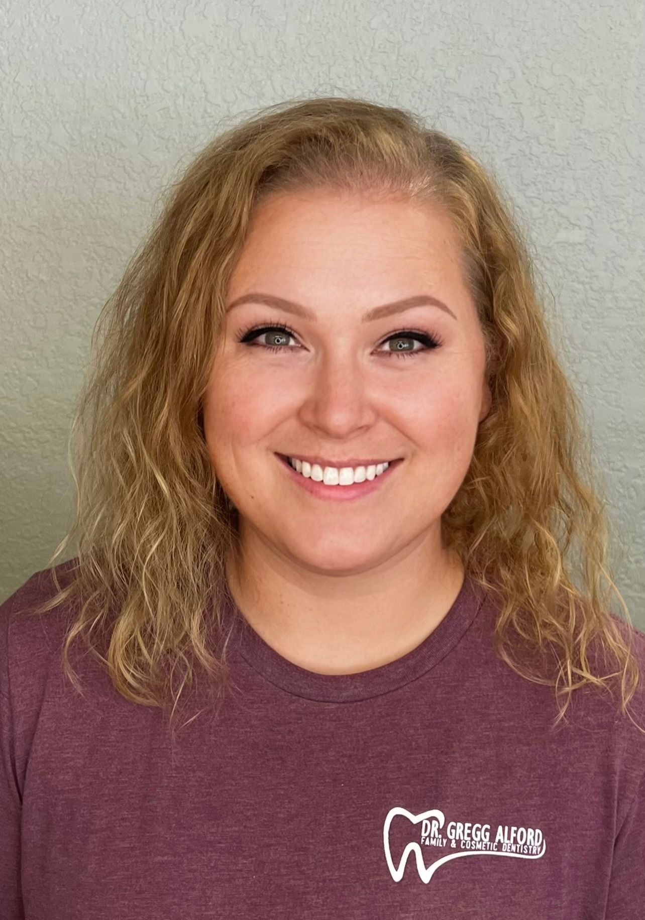 A woman in a green shirt is smiling for the camera.