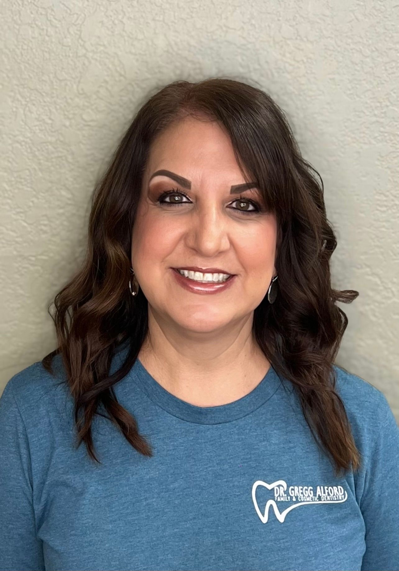 A woman in a green shirt is smiling for the camera.