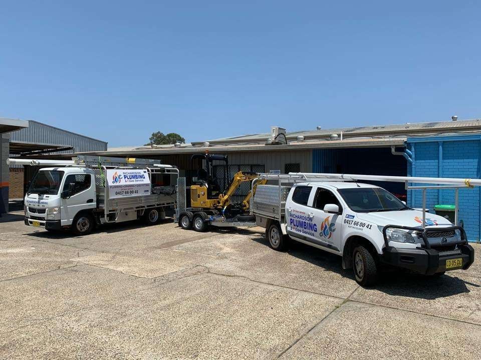 Two Trucks And A Trailer Are Parked In Front Of A Building — Richardson Plumbing & Gas Service In Port Macquarie, NSW