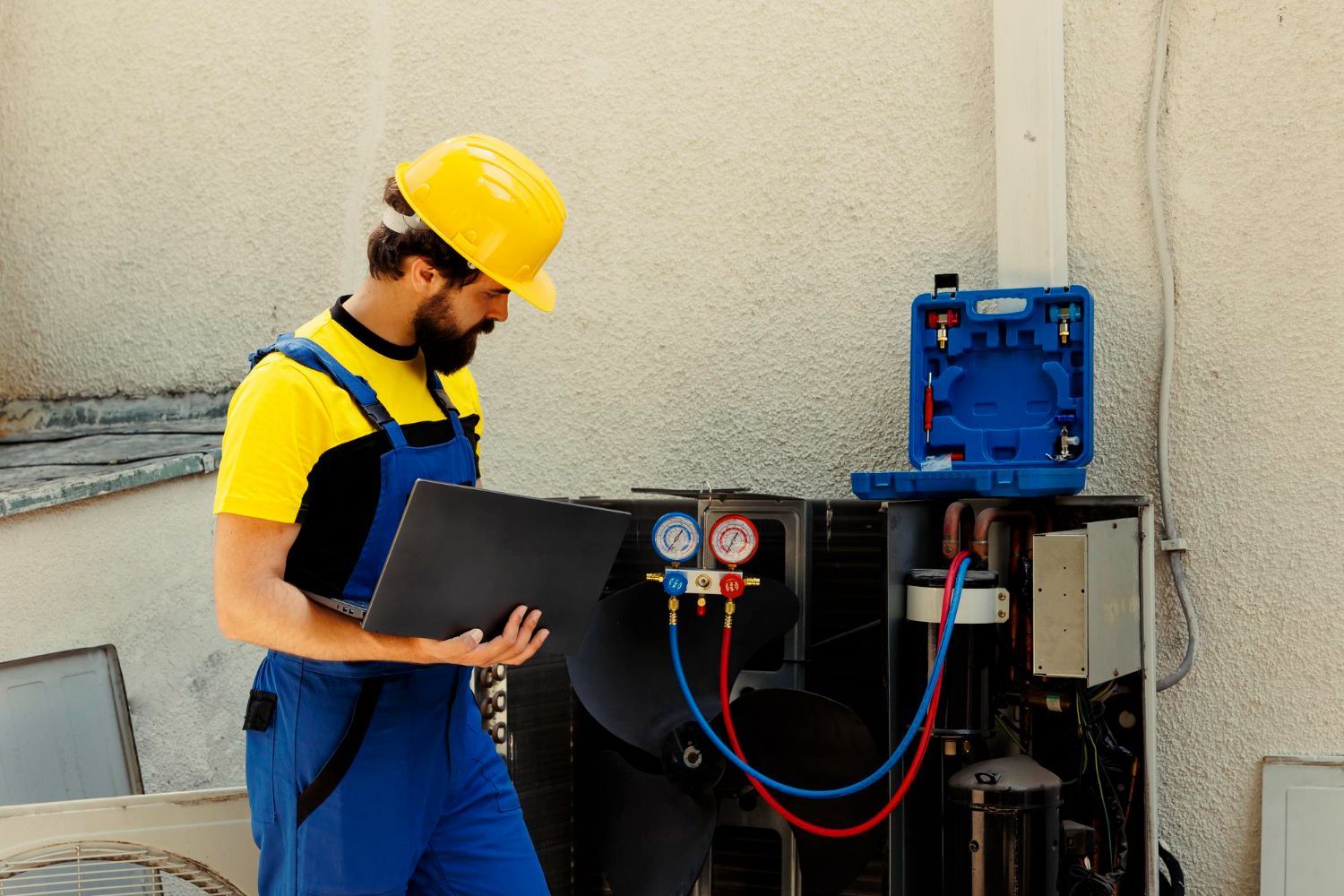 A man in a hard hat is working on an air conditioner.