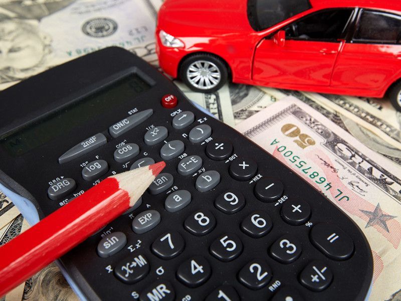 Calculator, red pencil, and toy car on cash; budgeting for a purchase.