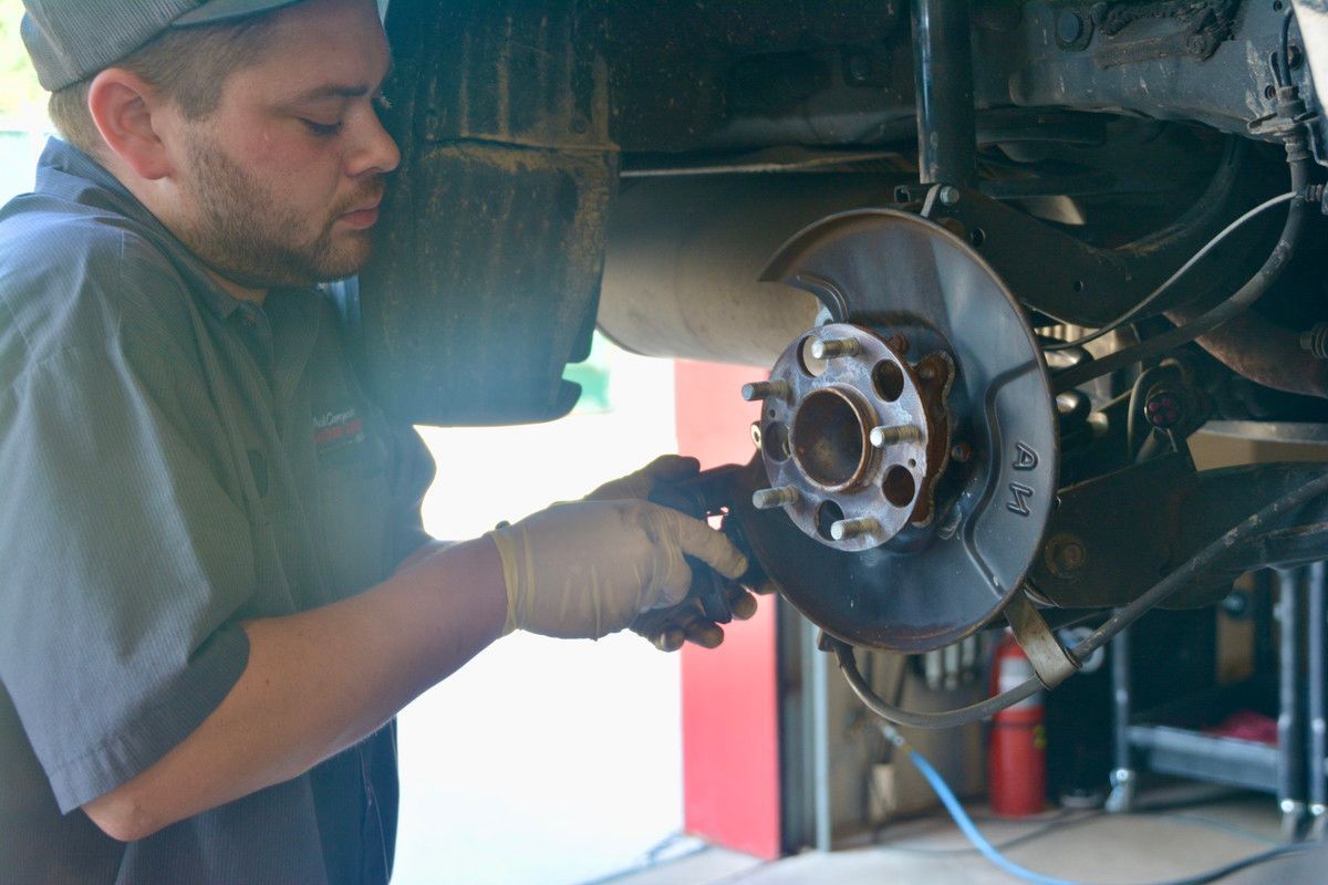 A man is working on the brake rotor of a car. | Paul Campanella's Auto Centers