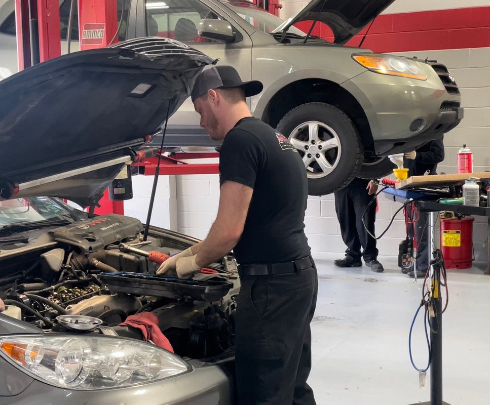 A man is working on the engine of a car in a garage.