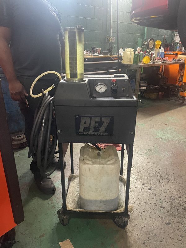 Black PFZ fluid exchange machine on a rolling cart in a shop. A person stands nearby.