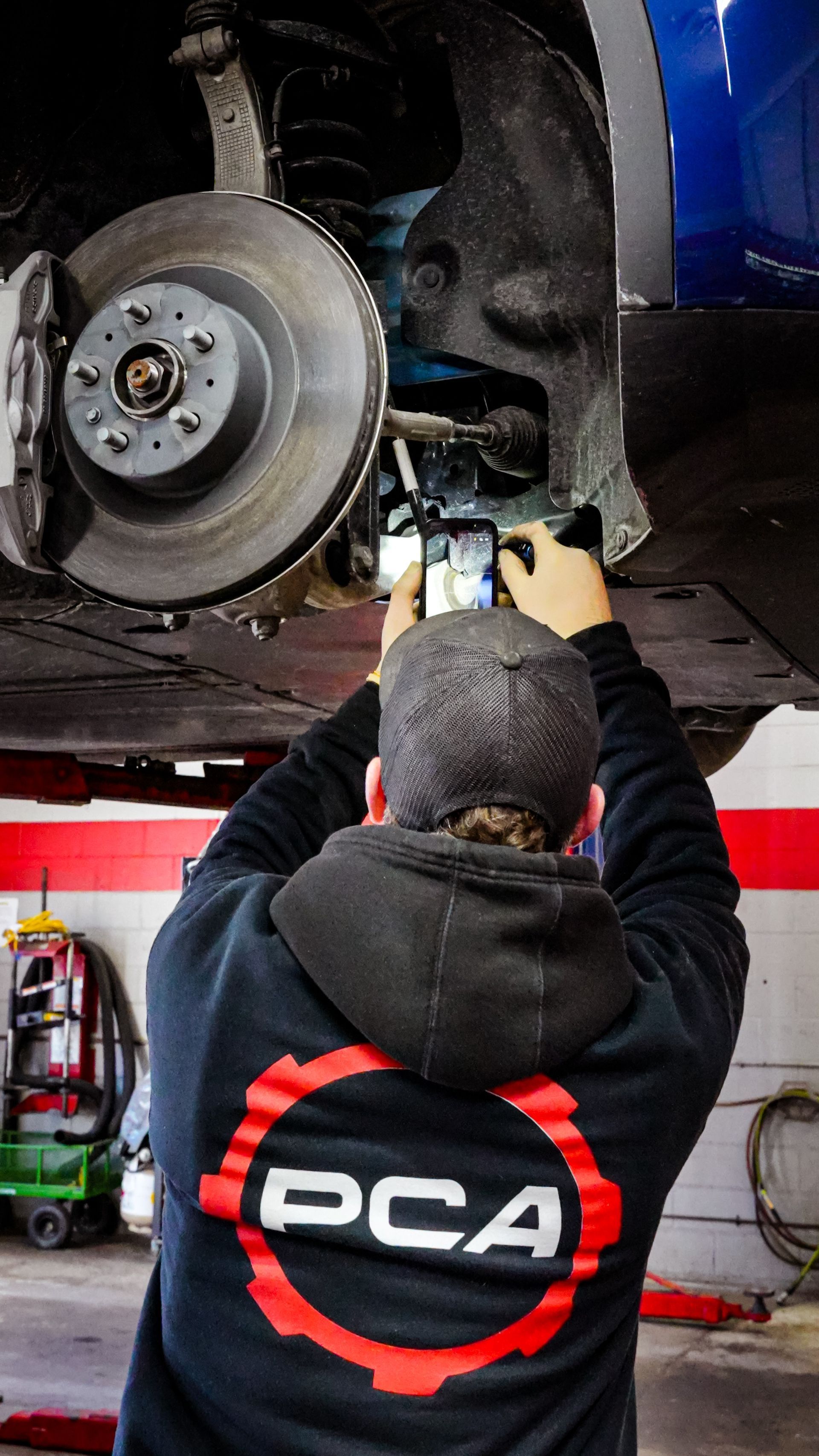 Technician at Paul Campanella’s Auto Centers inspecting a vehicle’s suspension and brake components.