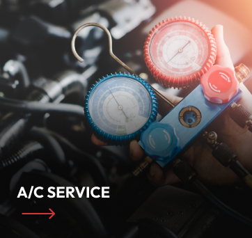 A mechanic using gauges to service a car's air conditioning system.