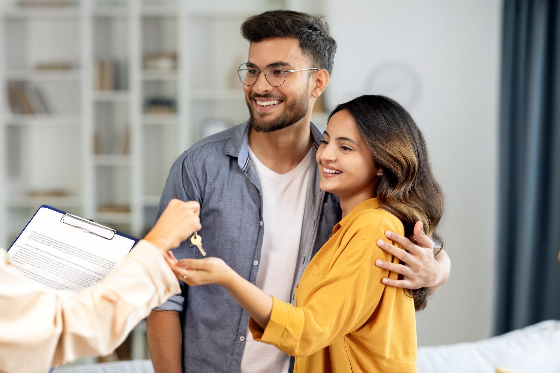 Real estate agent showing a couple a home; open wooden door, pointing.