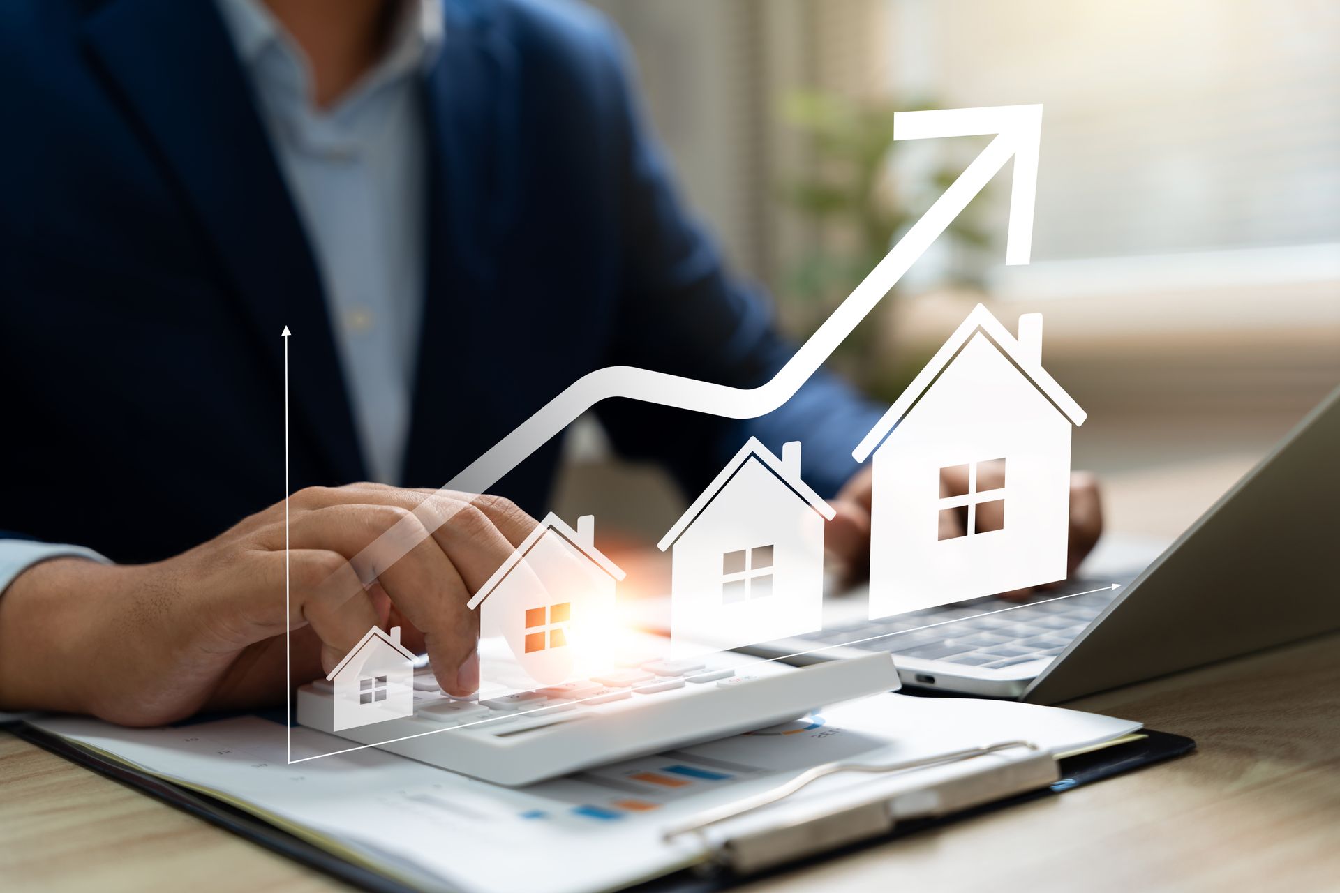 Man using calculator with house-shaped graphics and upward-trending arrow on laptop, symbolizing real estate growth.