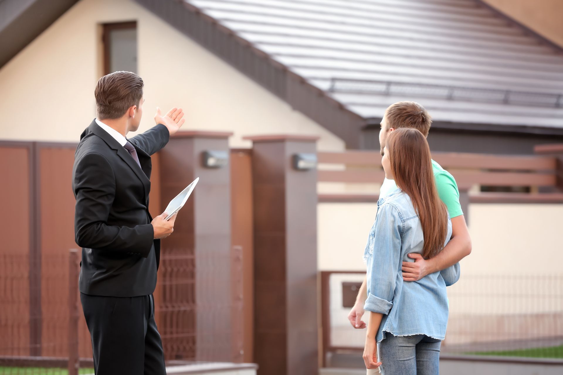 Real estate agent showing a couple a house, pointing to the roof.