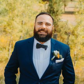 A man with a beard is wearing a suit and bow tie.