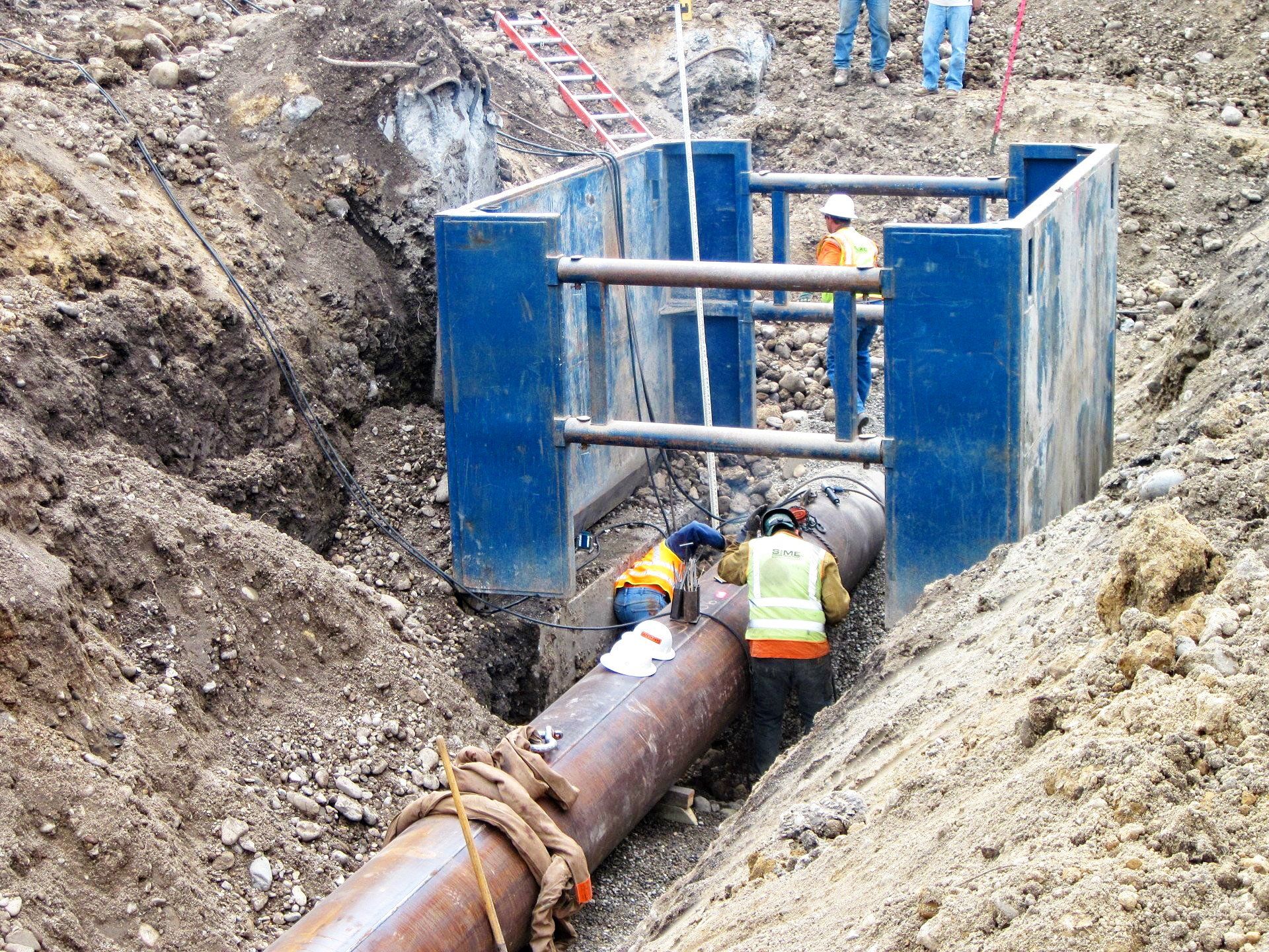 A group of construction workers are working on a pipe in the dirt