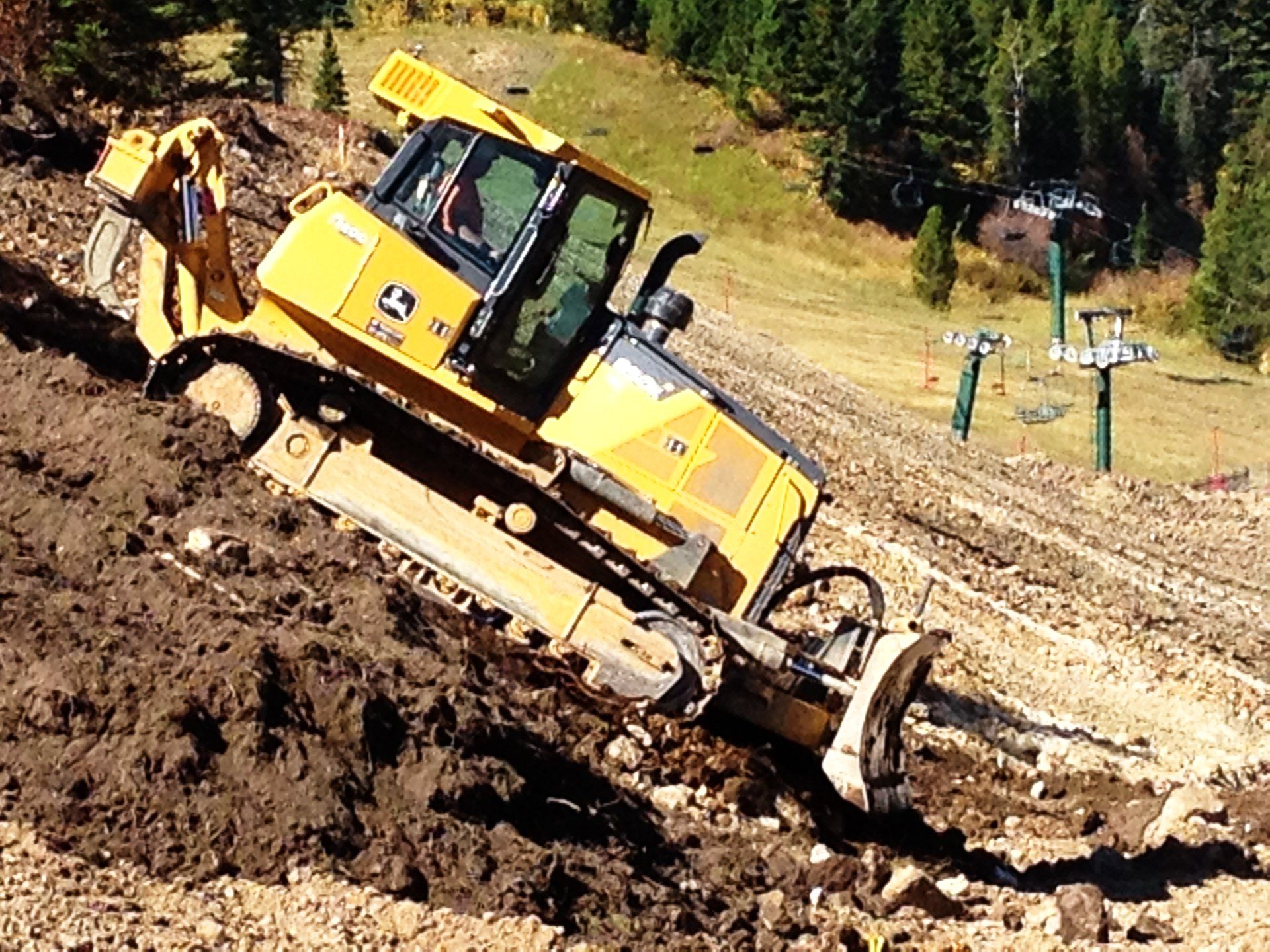 A yellow bulldozer is driving down a dirt hill.