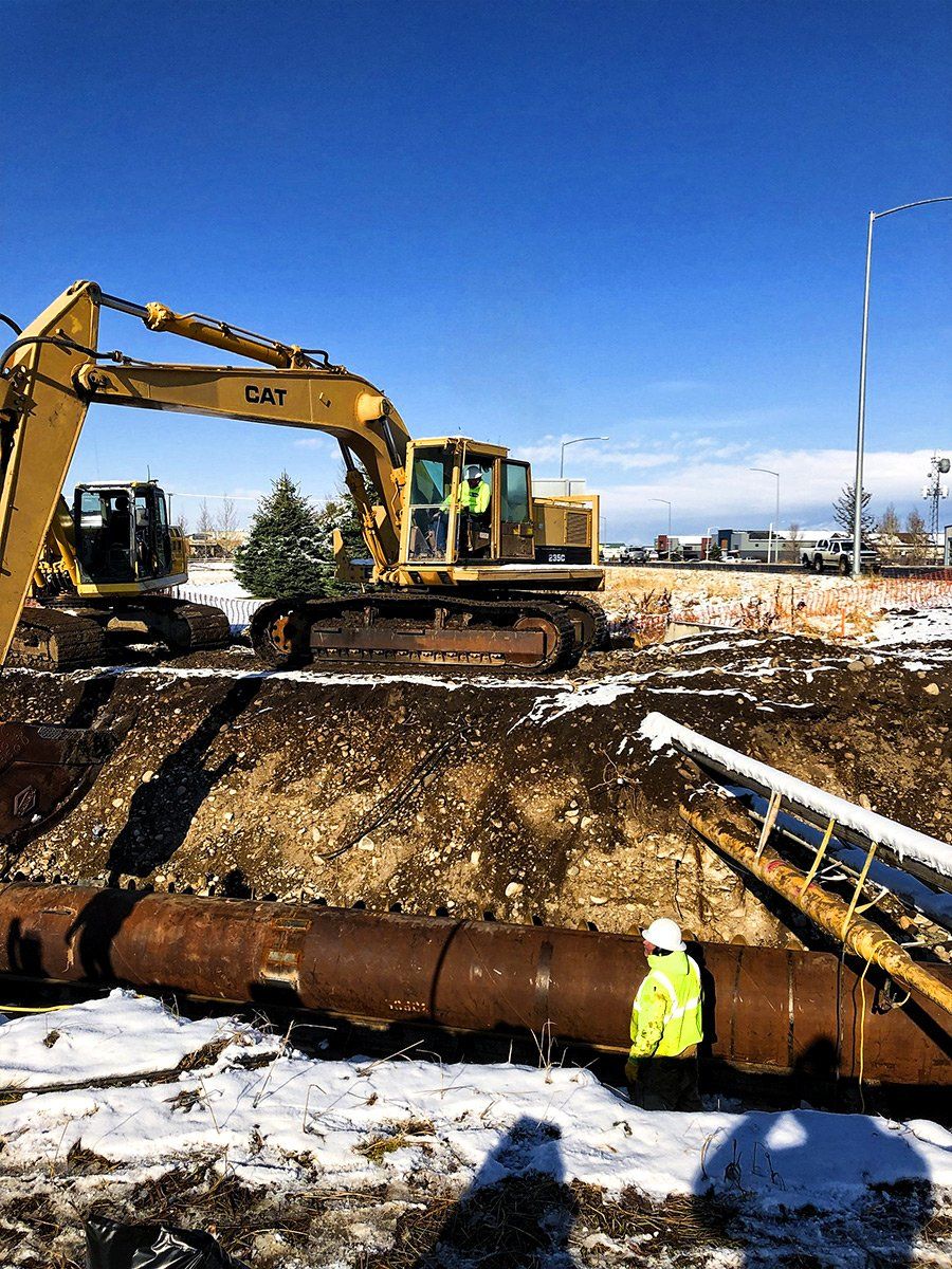 A construction site with a bulldozer and pipes in the dirt.
