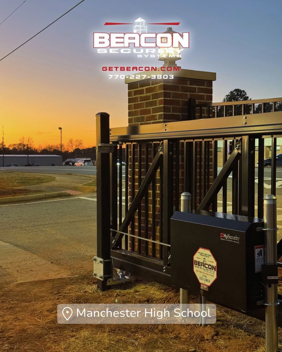 Automatic gate with Beacon Security logo at Manchester High School at sunset.