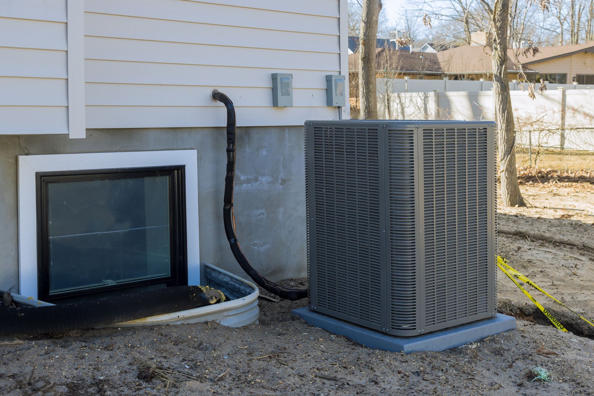 An air conditioner is sitting on the side of a house next to a window.