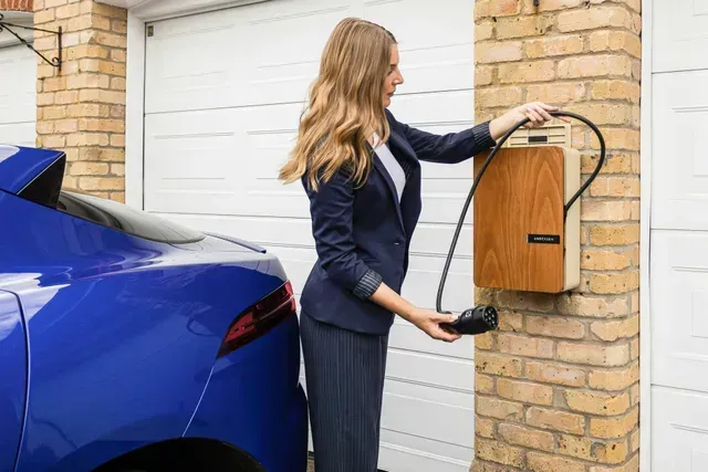 Woman installing an electric vehicle wall charger at home.