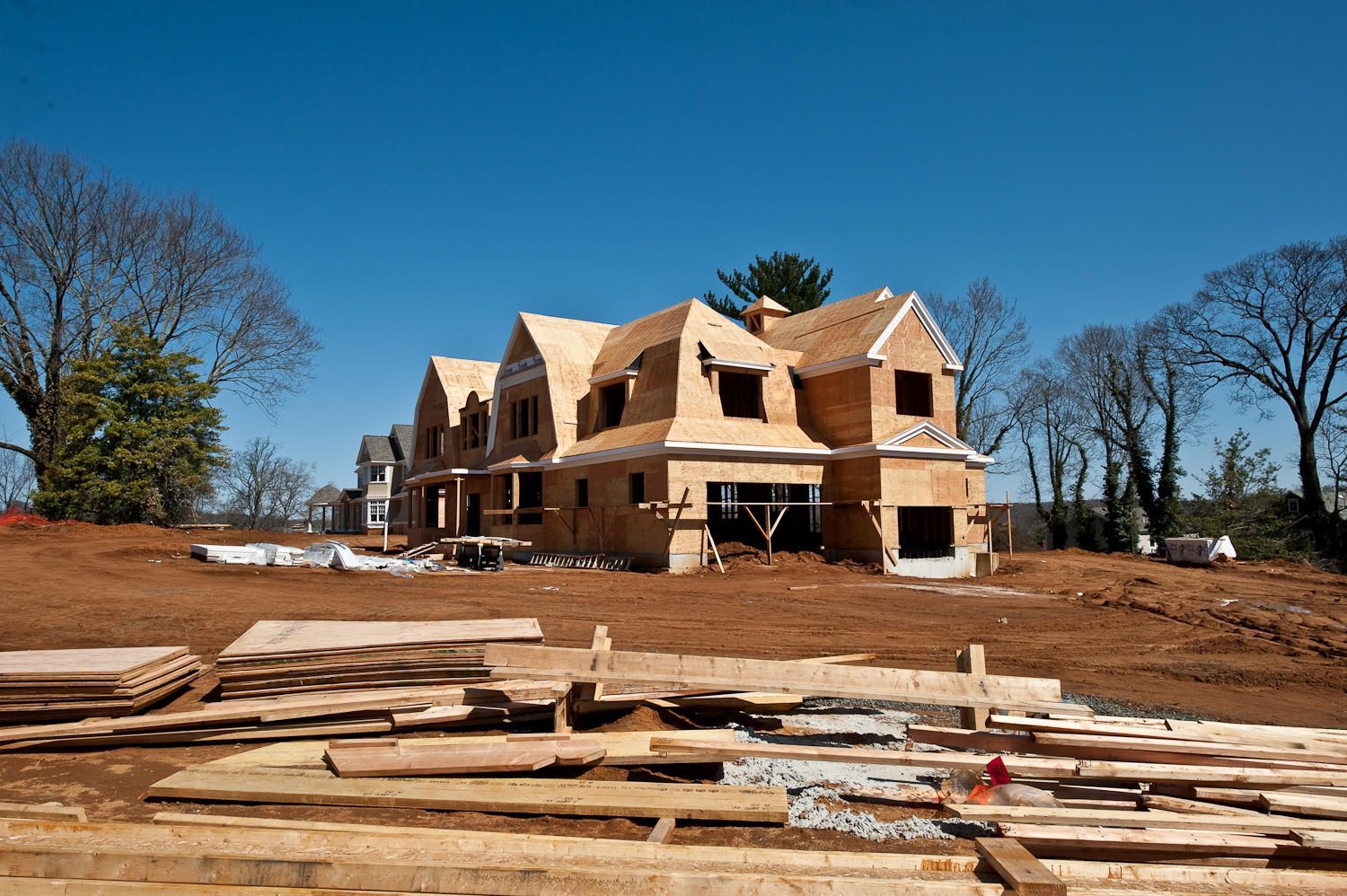 A large house is being built in the middle of a dirt field.