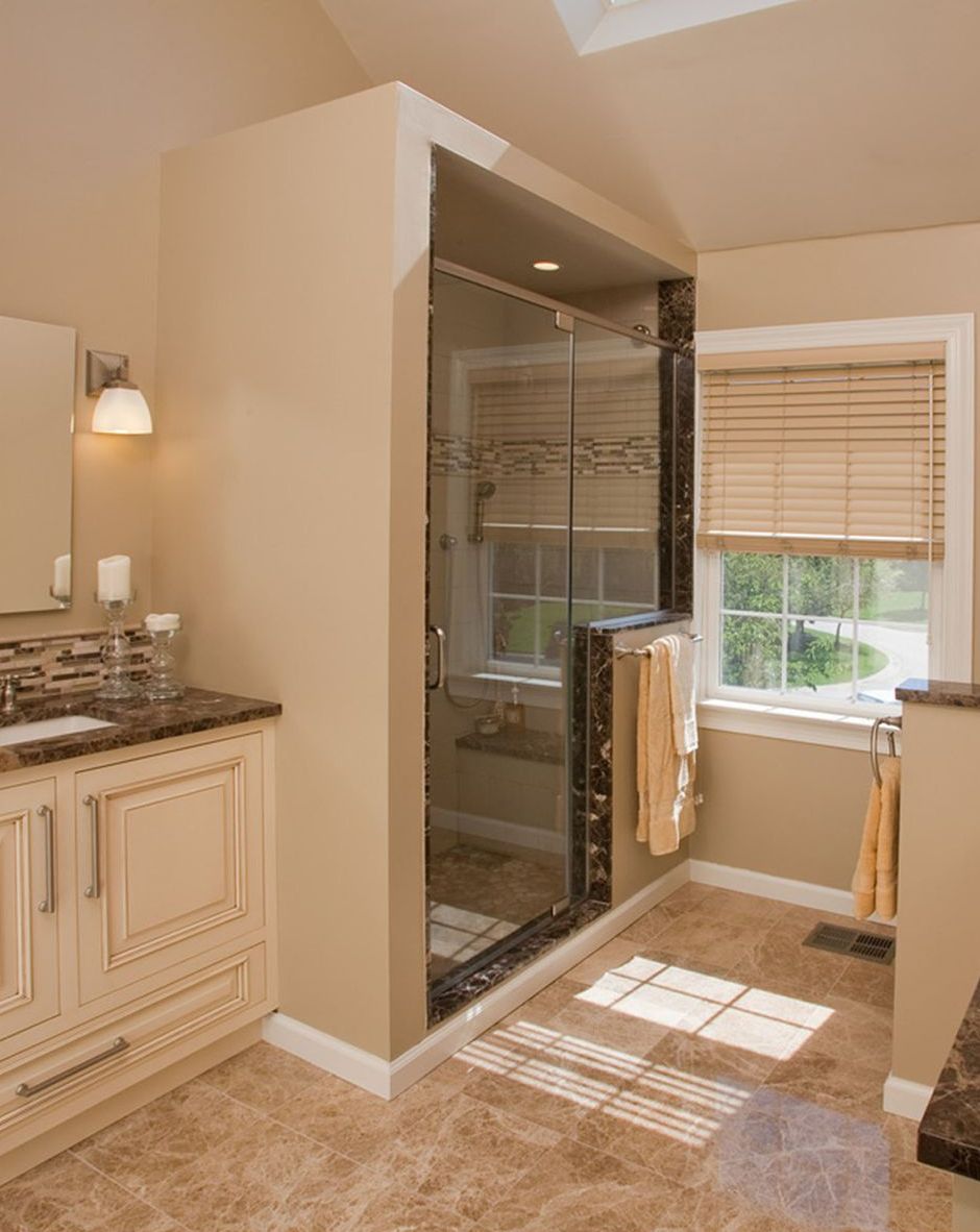 A bathroom with a walk in shower , sink , mirror and window.