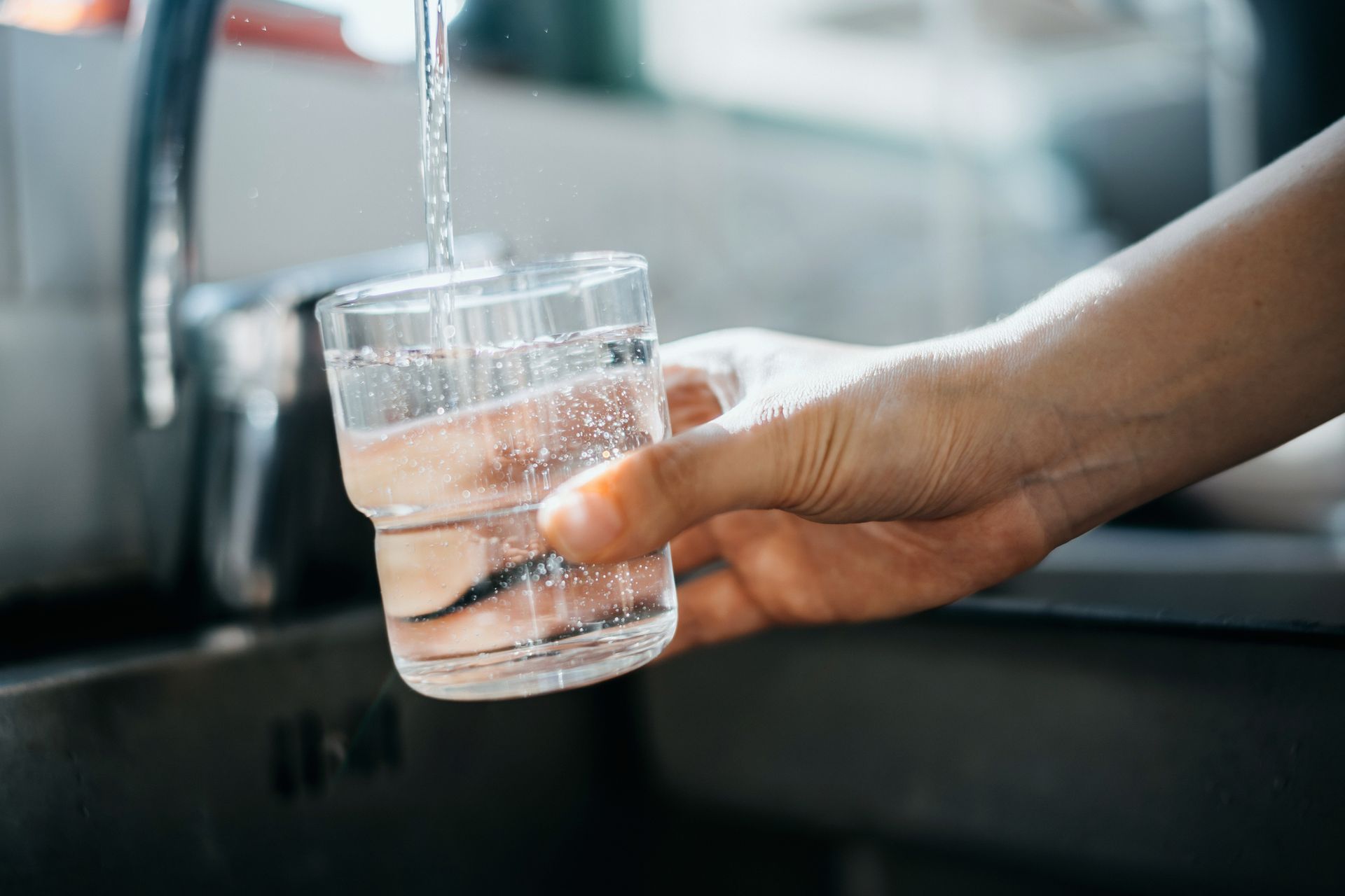 A person presenting a glass of water obtained from a faucet, illustrating water treatment in Seabeck