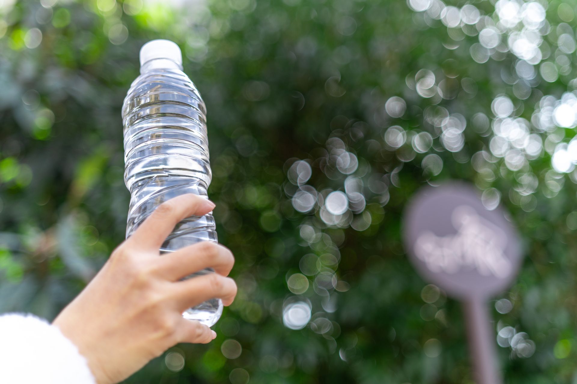 A hand holding a plastic bottle full of water.