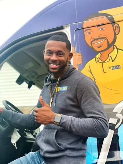 A man is sitting in the driver 's seat of a van giving a thumbs up.