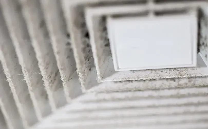 A close up of a dirty air vent in a room.