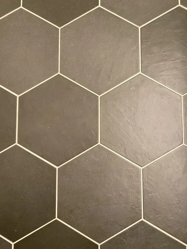 A close up of a hexagon tile floor with white grout.