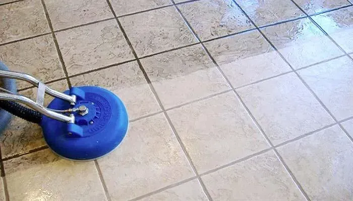 A person is cleaning a tile floor with a machine.