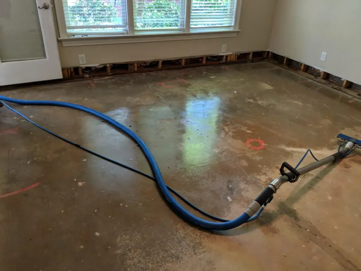 A vacuum cleaner is sitting on a dirty concrete floor in a room.