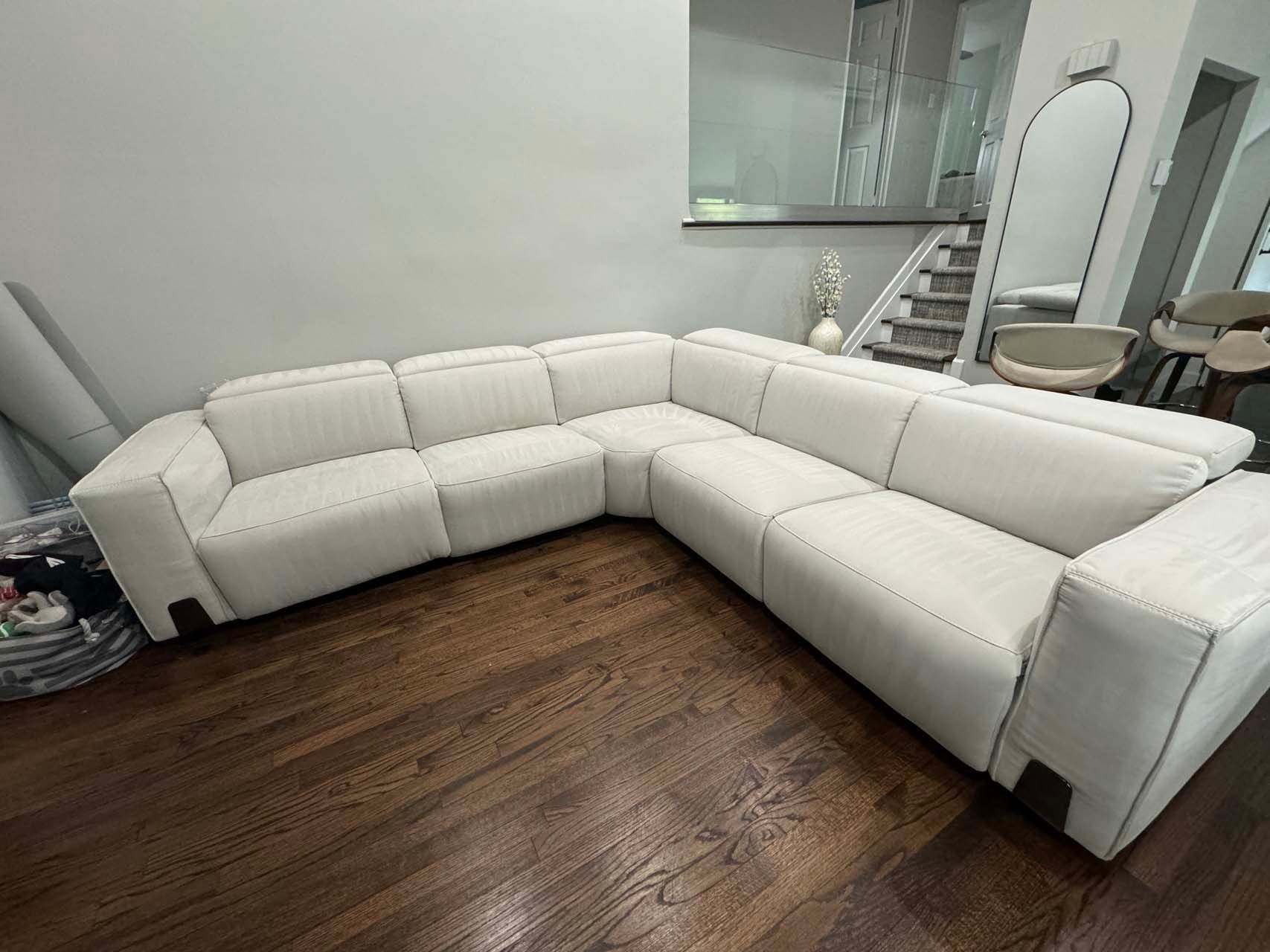 A white sectional couch is sitting on a wooden floor in a living room.