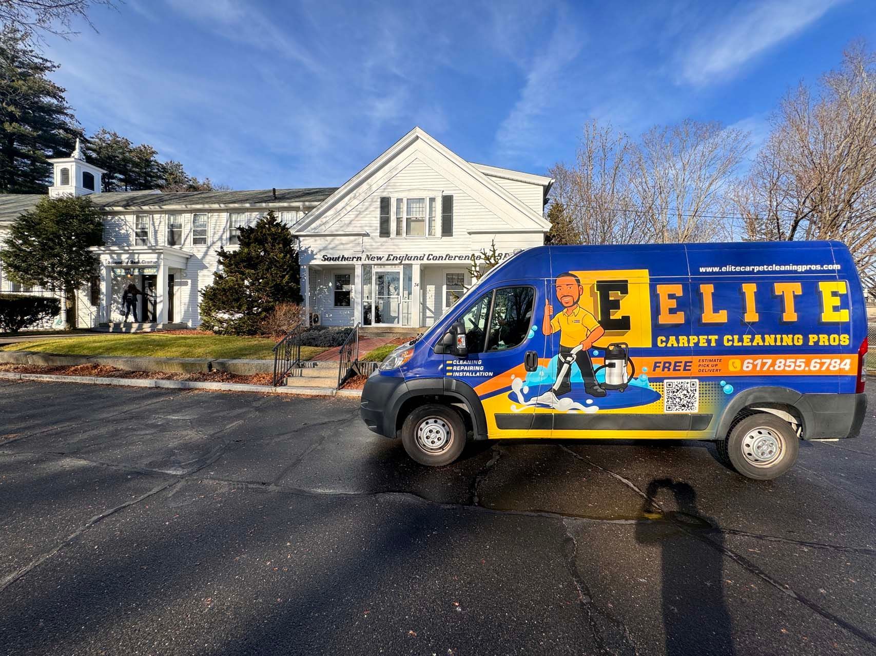 An elite carpet cleaning van is parked in front of a house.