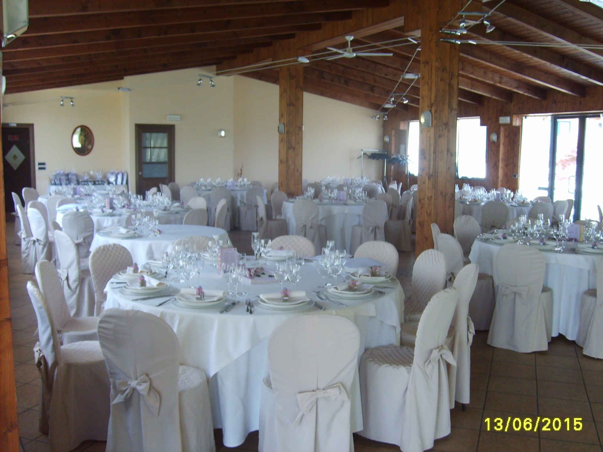 Una sala per banchetti allestita per un evento con tavoli rotondi, tovaglie bianche e coprisedie.