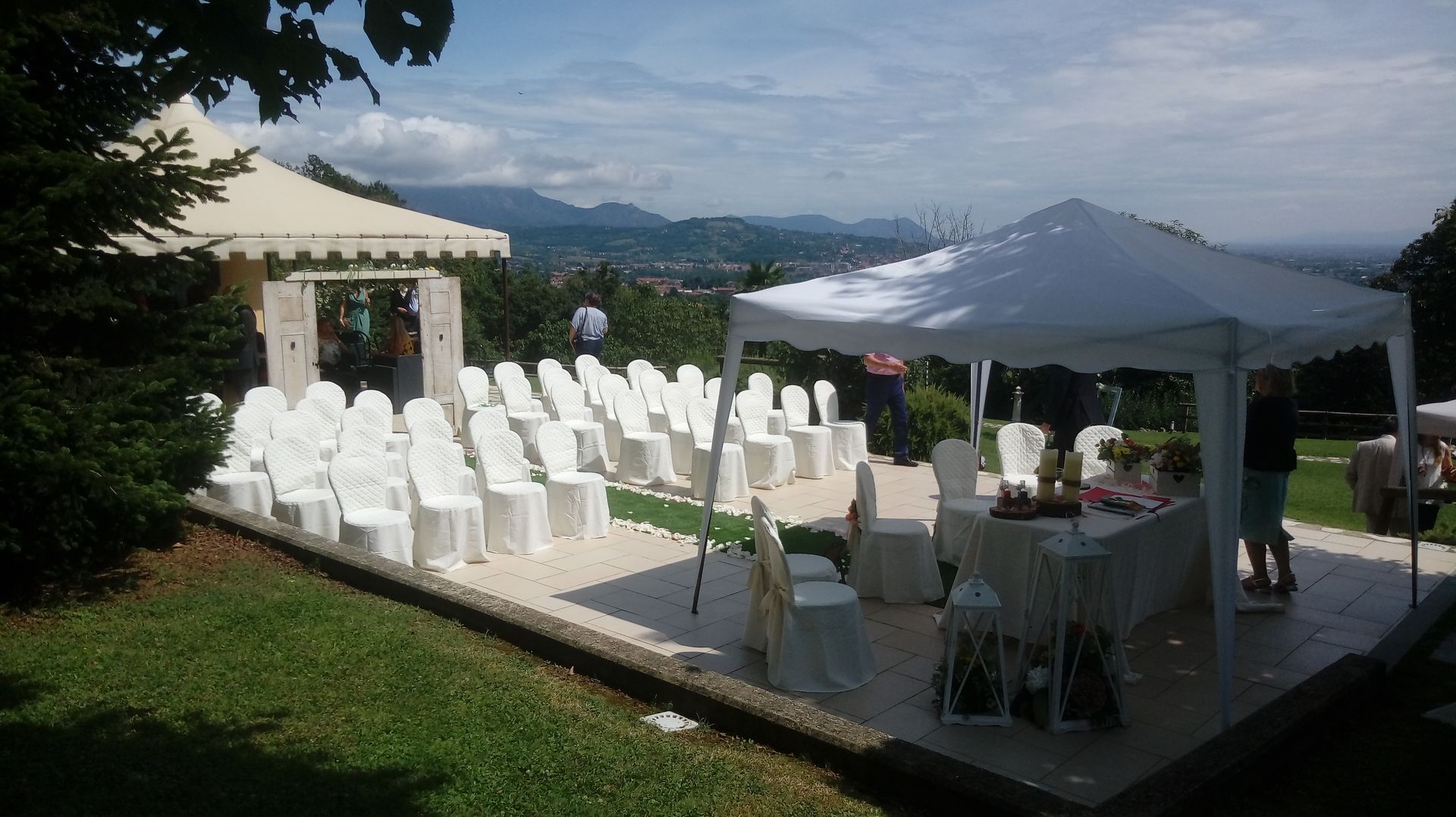 Cerimonia nuziale all'aperto con sedie bianche, tende e vista sulle montagne.