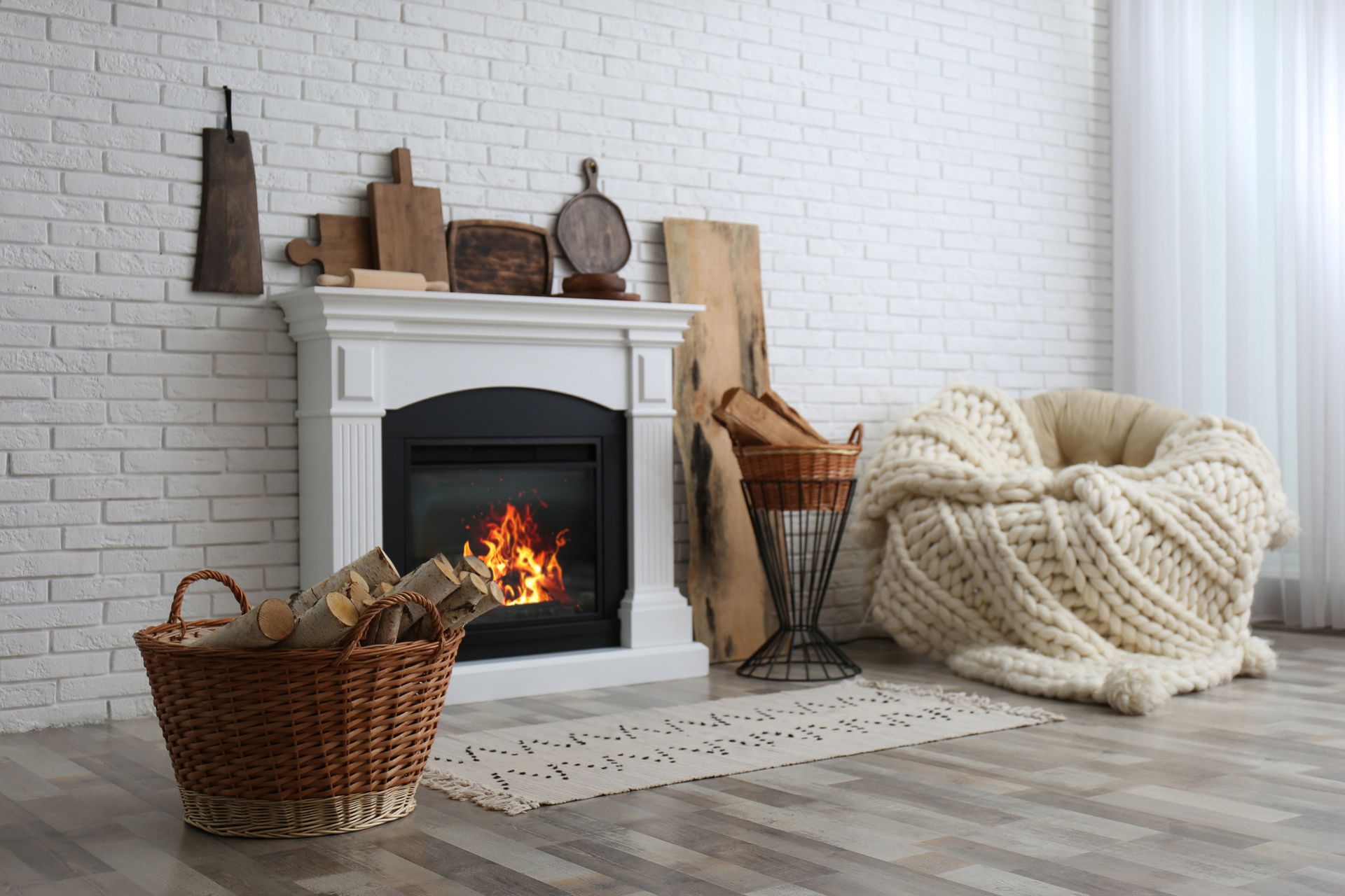 A living room with a fireplace and a basket of logs.