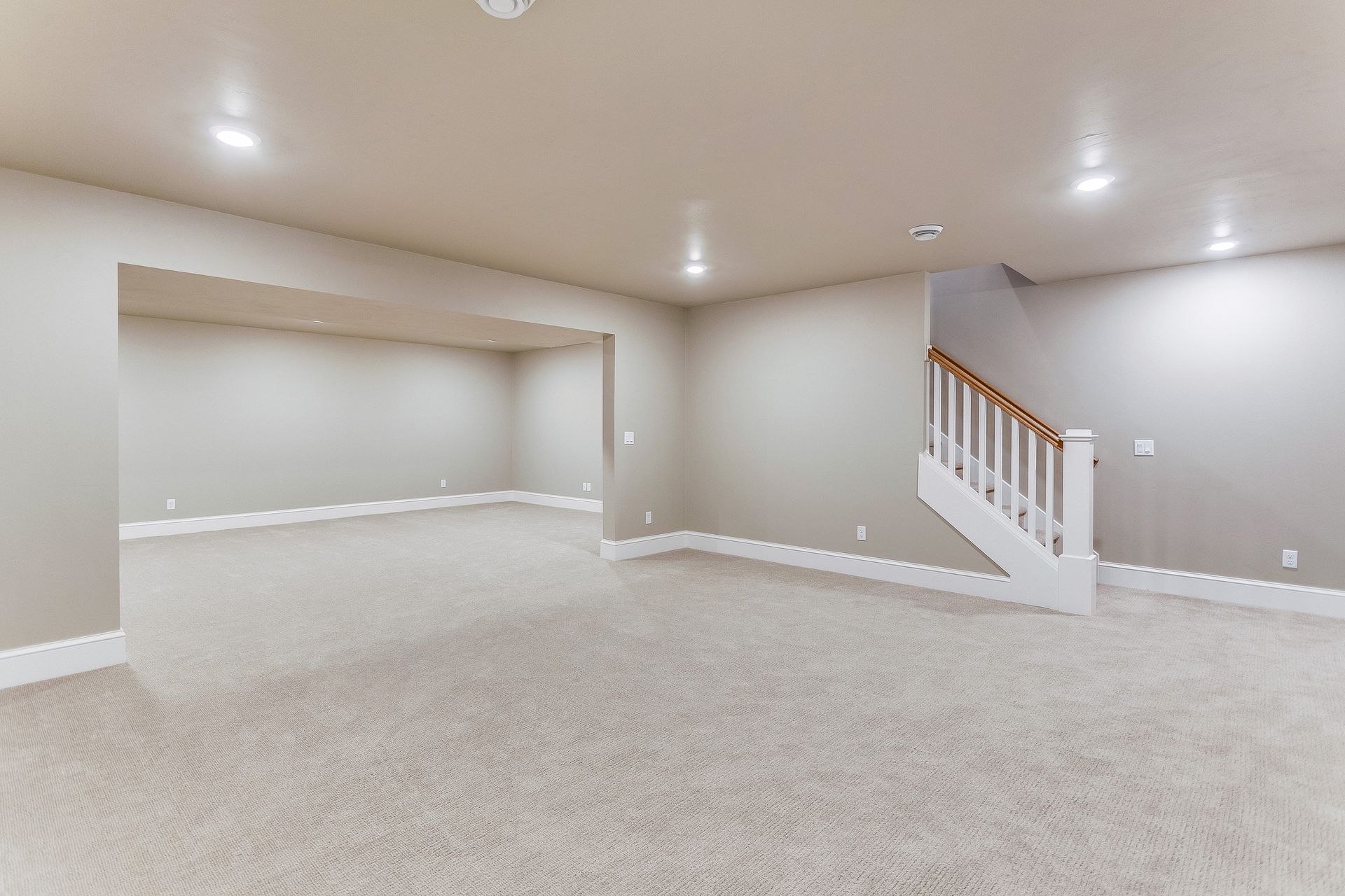 An empty basement with a staircase leading up to the second floor.