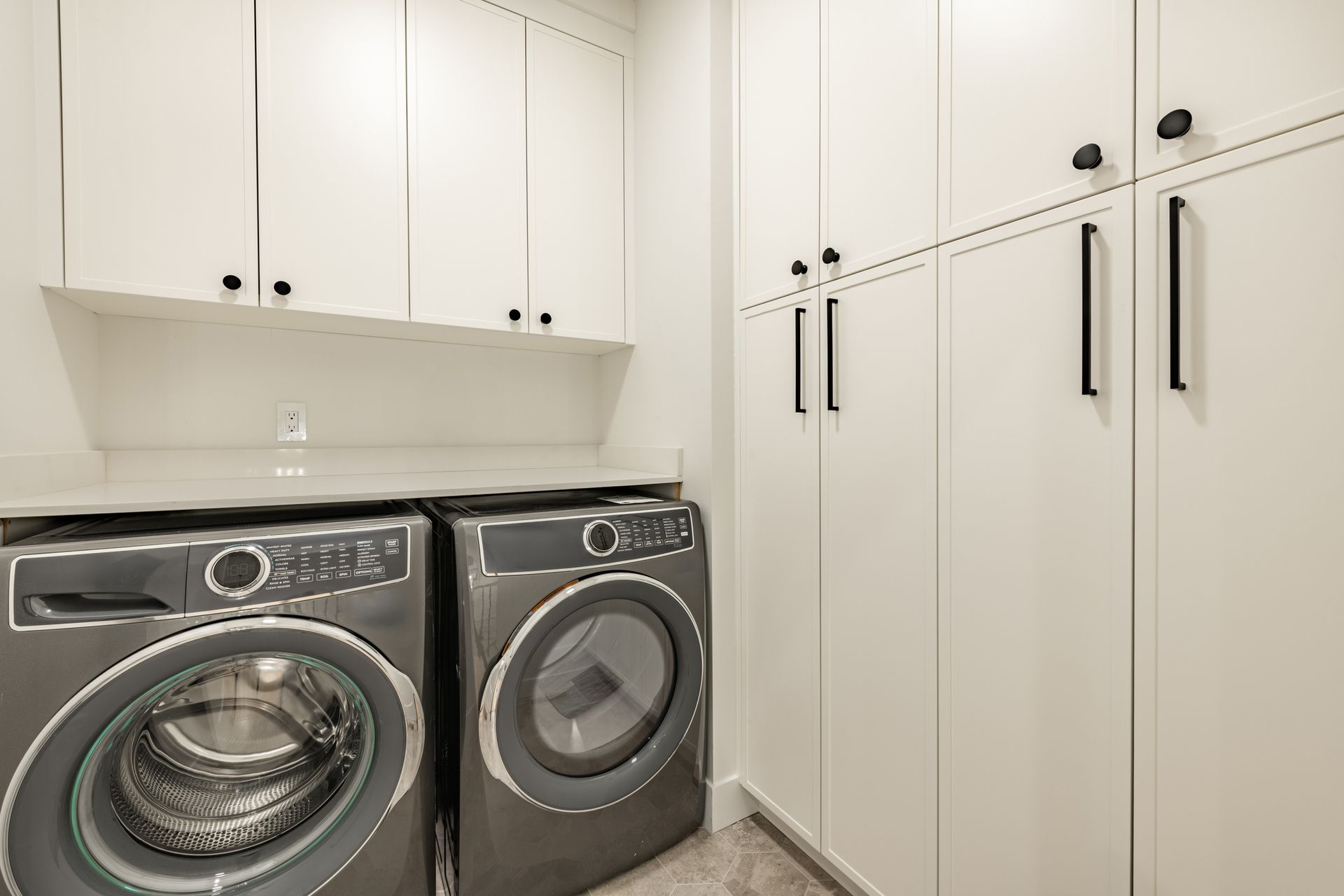 A laundry room with a washer and dryer and white cabinets.
