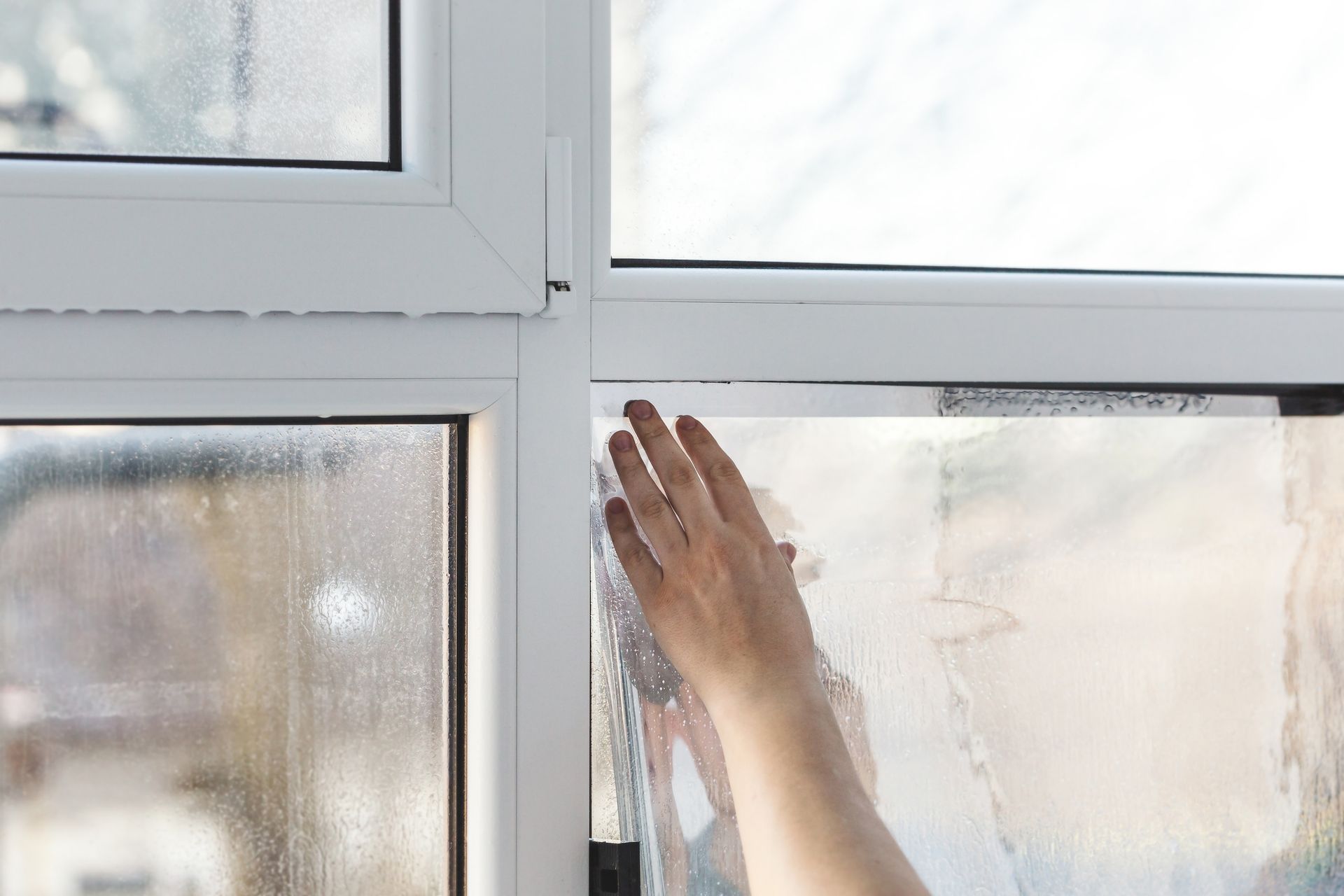 A woman is cleaning a window with her hand.