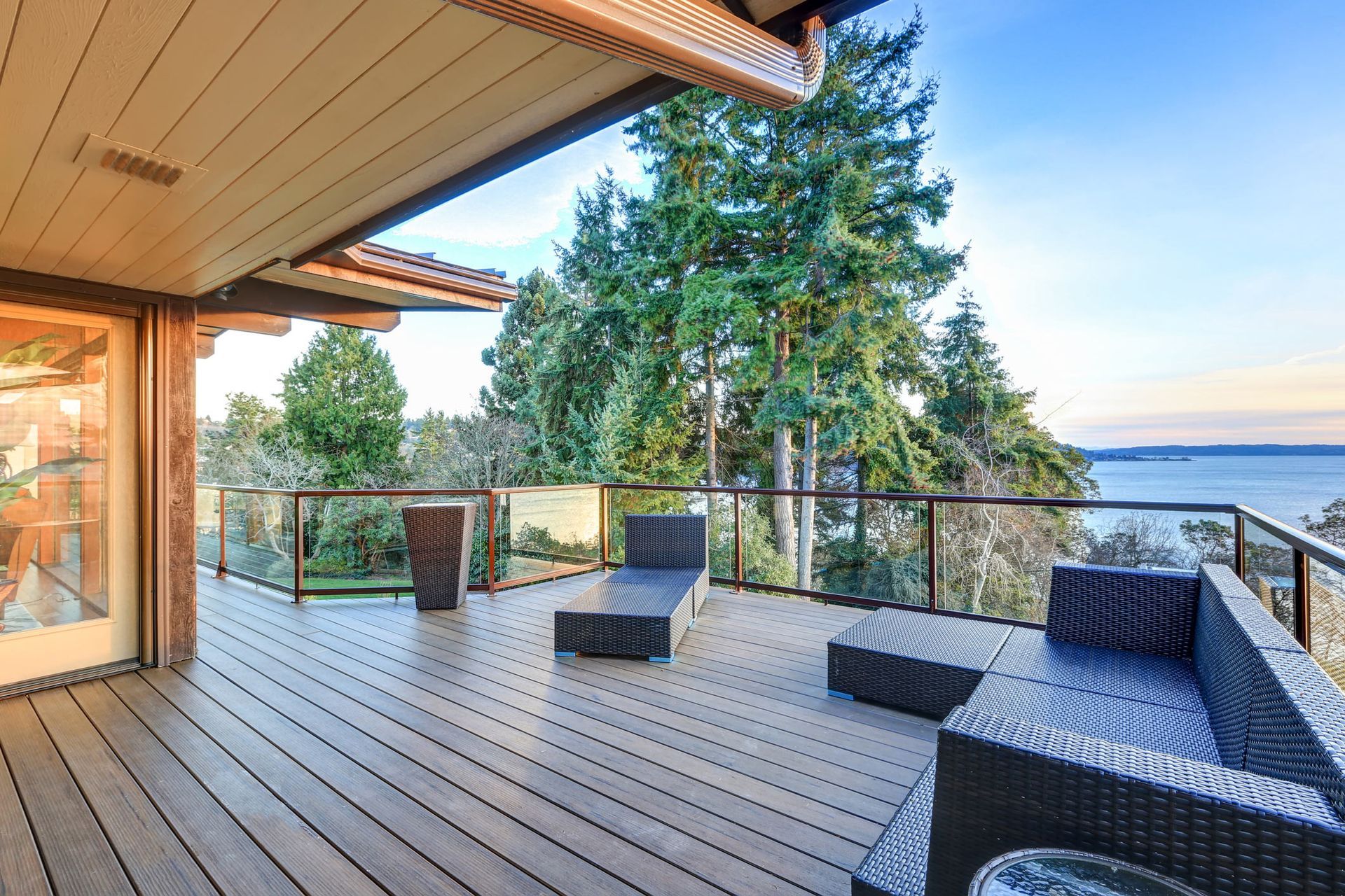A large deck with a view of the ocean and trees.