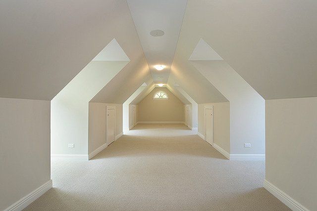 An empty hallway with a vaulted ceiling and a light on the ceiling.