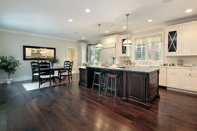 A kitchen and dining room in a house with hardwood floors and white cabinets.