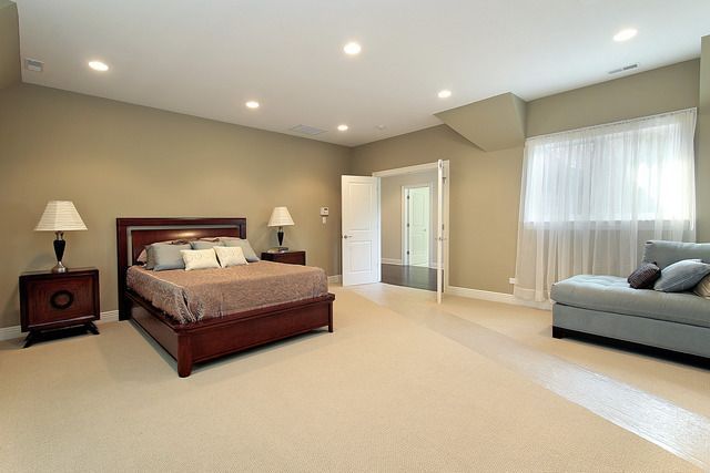 A bedroom with a bed , chair , nightstand and lamps.