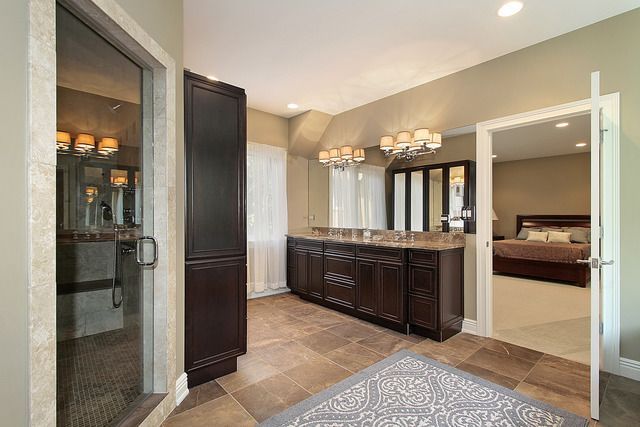 A bathroom with two sinks , a walk in shower and a rug.