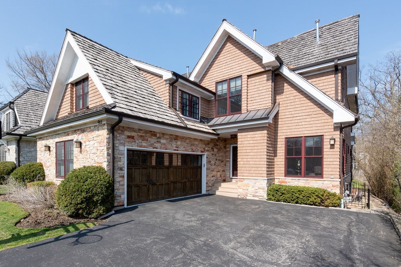 A large brick house with a wooden garage door is for sale.