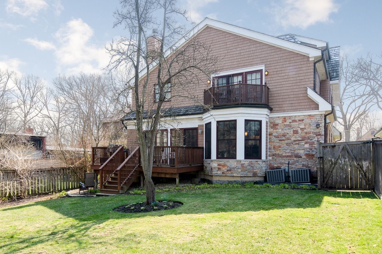 The backyard of a house with a large lawn and a deck.